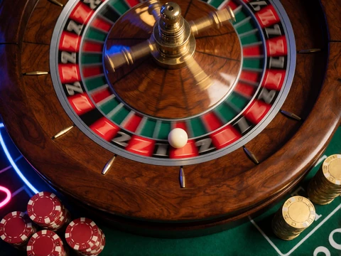 Roulettekessel aus Holz mit wei&szlig;er Kugel im roten Fach und goldenen Chips im Online Casino Roulette